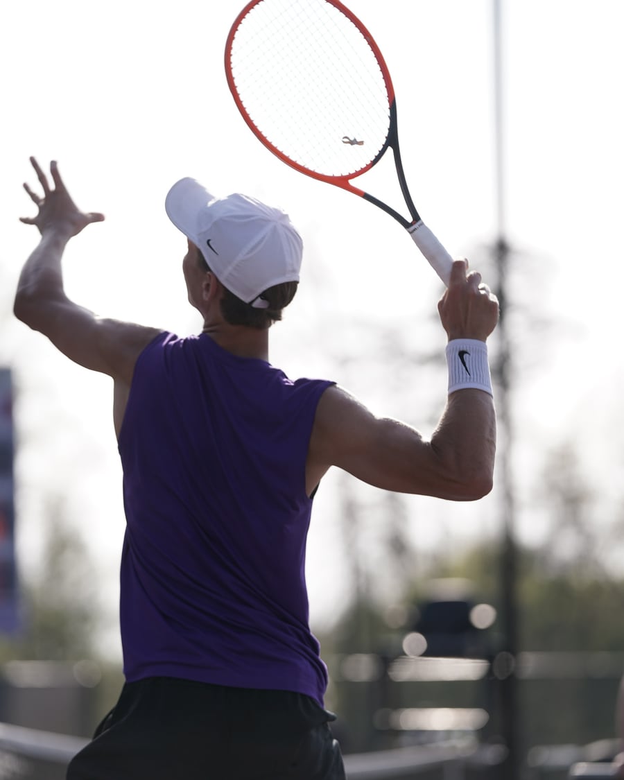 Player winding up to strike a ball on a hard court