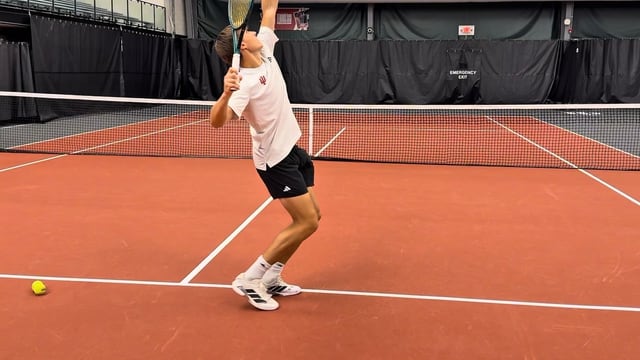 Player driving through the serve on an indoor clay court