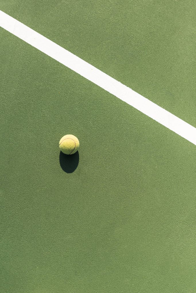 A tennis ball resting beside a court line